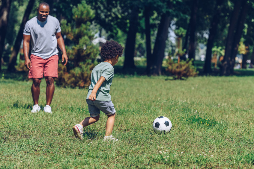 Dad plays soccer with his son during summer visitation.