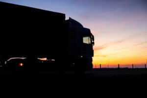 Image of a long haul truck on the road at sunset