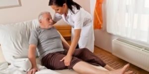 Image of a medical worker helping an elderly man in bed