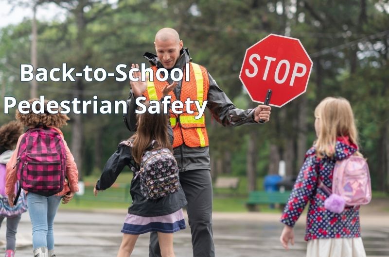 School crossing guard helping elementary school children safely cross the street during the morning commute.