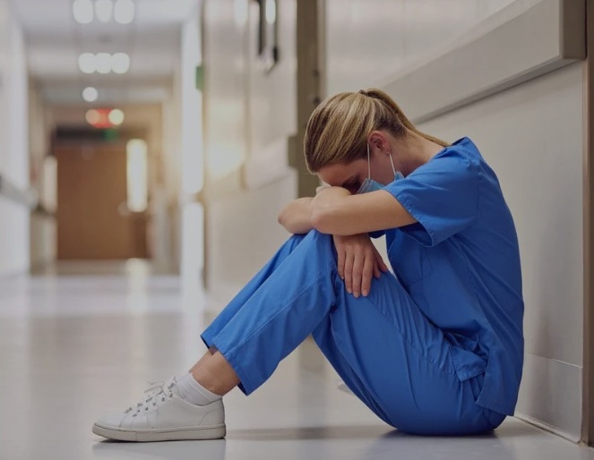 A nurse stressed out from health care wage theft.