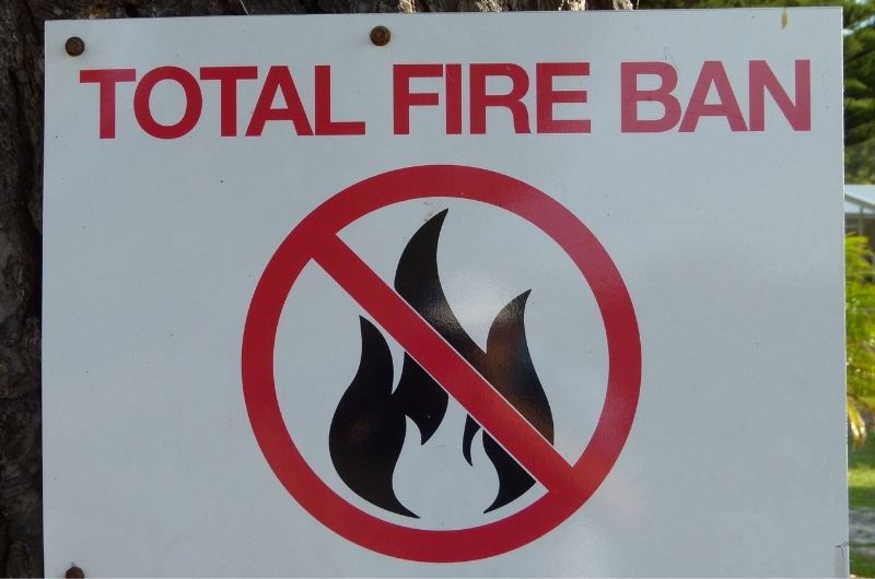 Fire ban warning sign pinned to a tree.