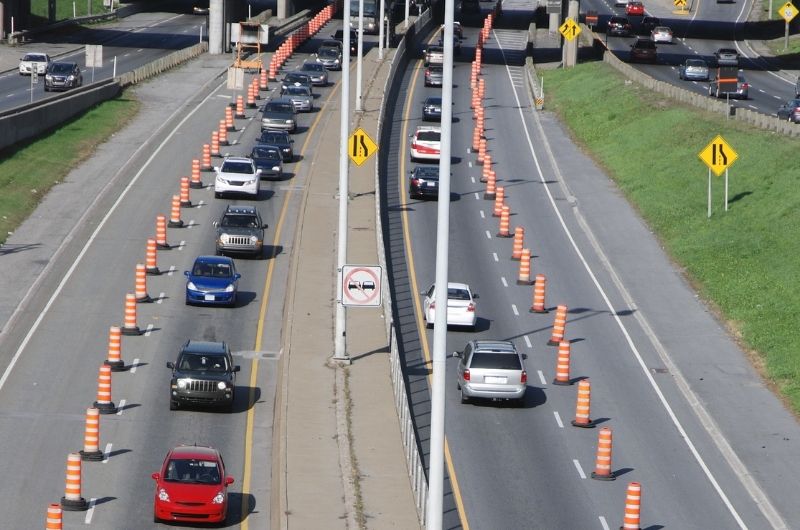 Cars and commercial trucks navigating changing lanes and construction barriers along Interstate 35 in Waco, Texas.