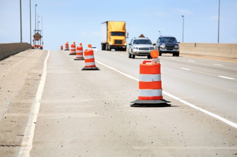 Cars and commercial trucks navigating changing lanes and construction barriers along Interstate 35 in Waco, Texas.
