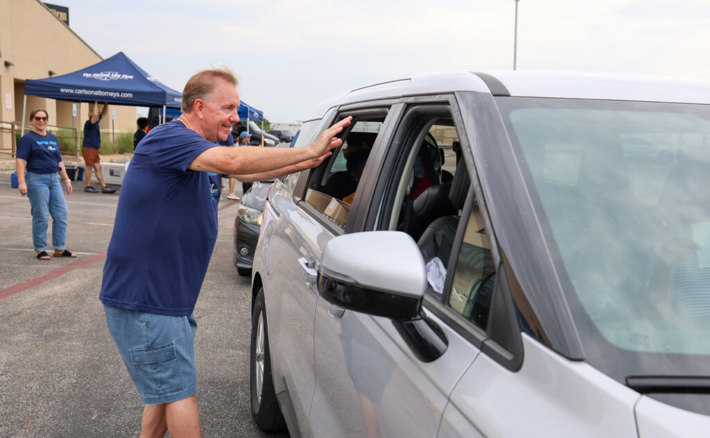 Craig Carlson waving to families at Carlson Cares Backpack Giveaway