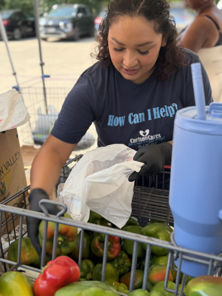 Carlson Cares volunteer bagging fresh peppers for Killeen Food Care Center clients.
