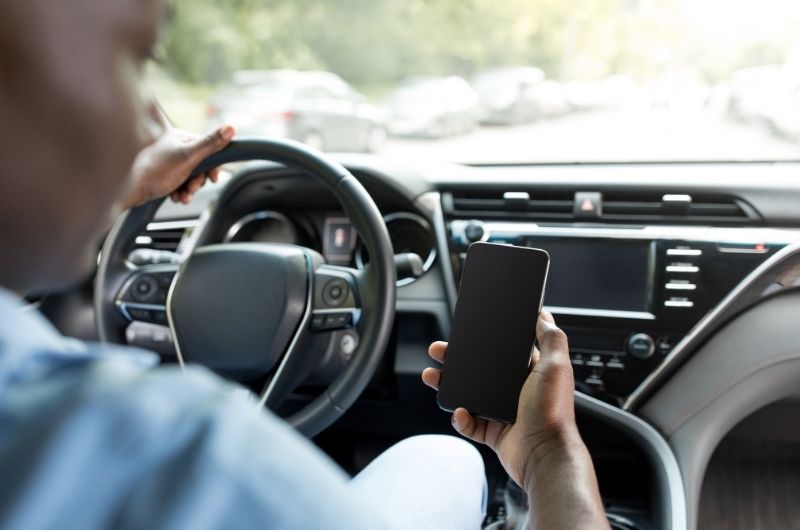 Driver using a cell phone while operating a vehicle in Texas traffic.