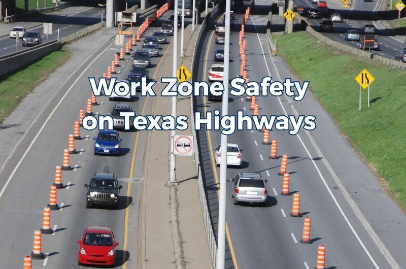 Traffic moving through a highway work zone in Texas with orange construction barrels, temporary barriers and reduced lanes.