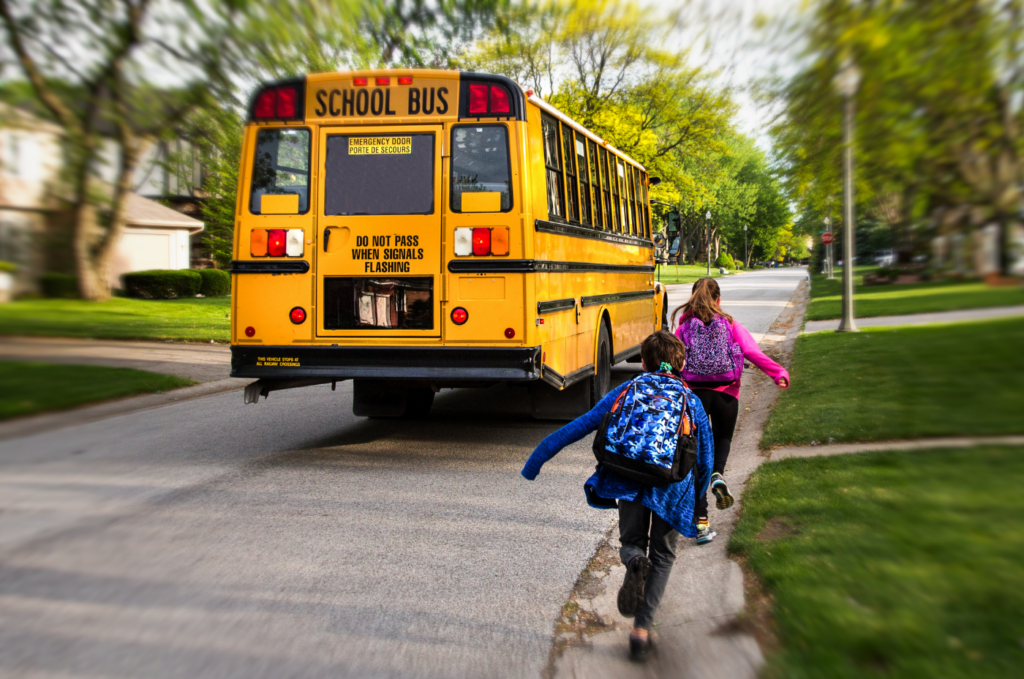 Children approaching a school bus on a residential street.
