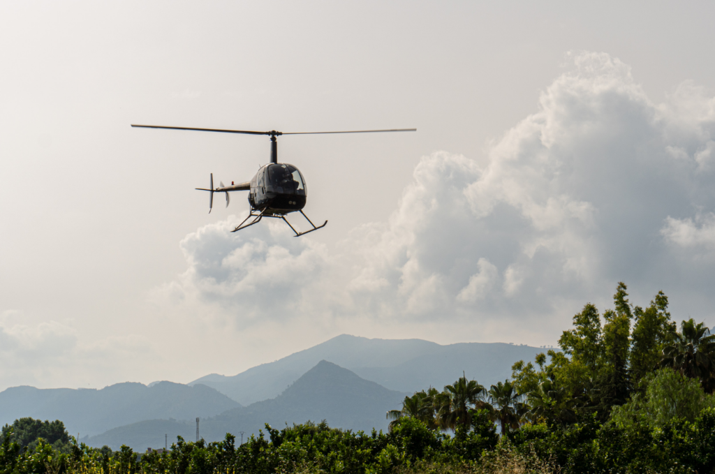 Helicopter flying above trees and mountains