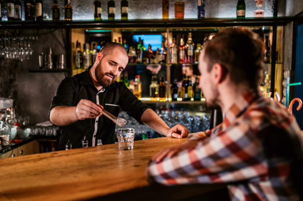 Bartender serving drinks to customers at a bar.