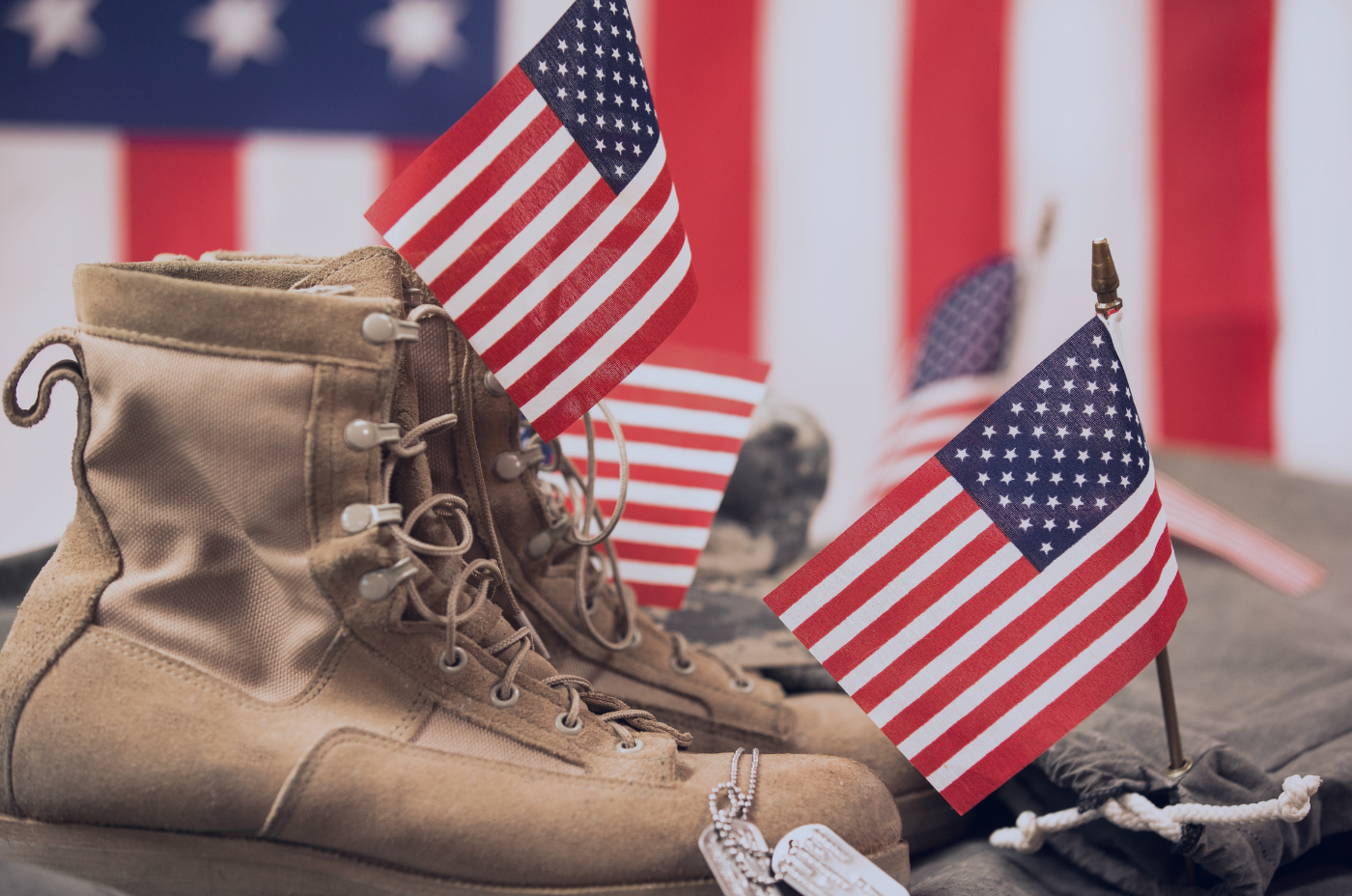 Military combat boots with dog tags and American flags displayed in remembrance of fallen service members