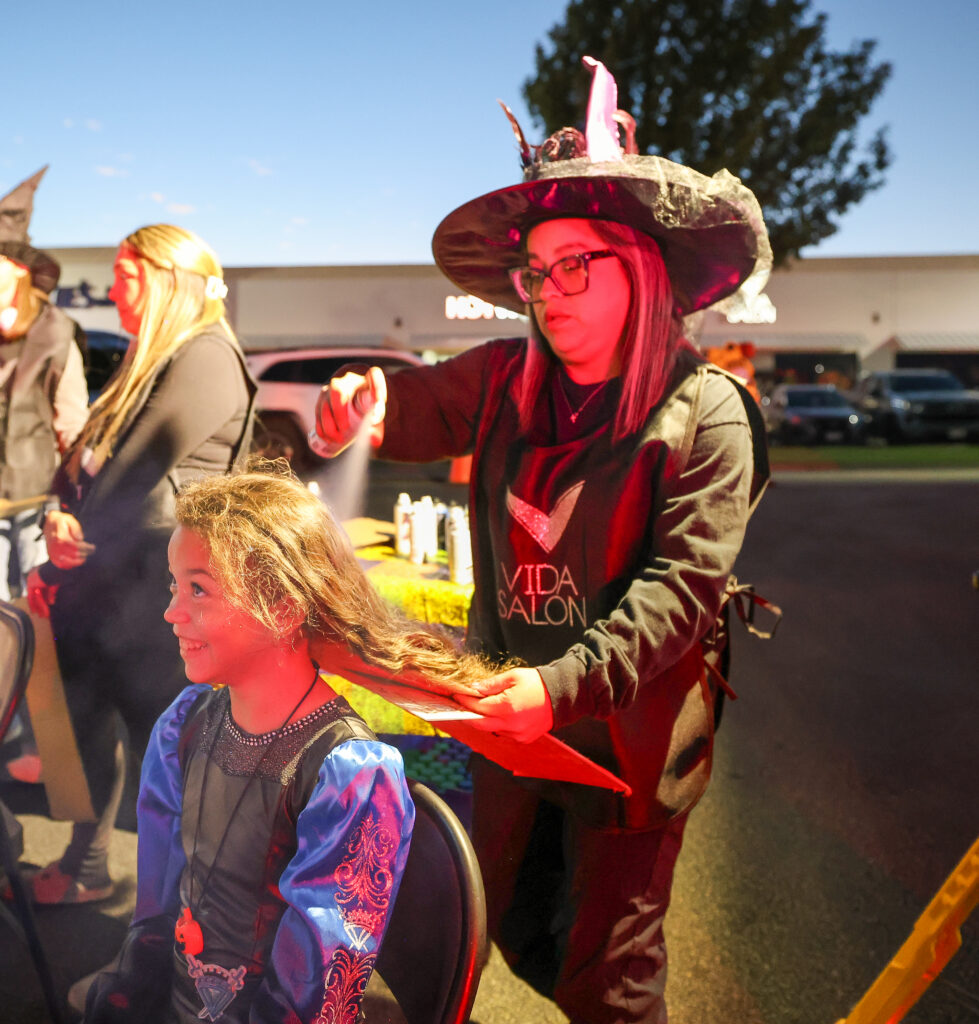 Vida Salon stylist colors a child's hair at the Carlson Cares Temple Trunk or Treat