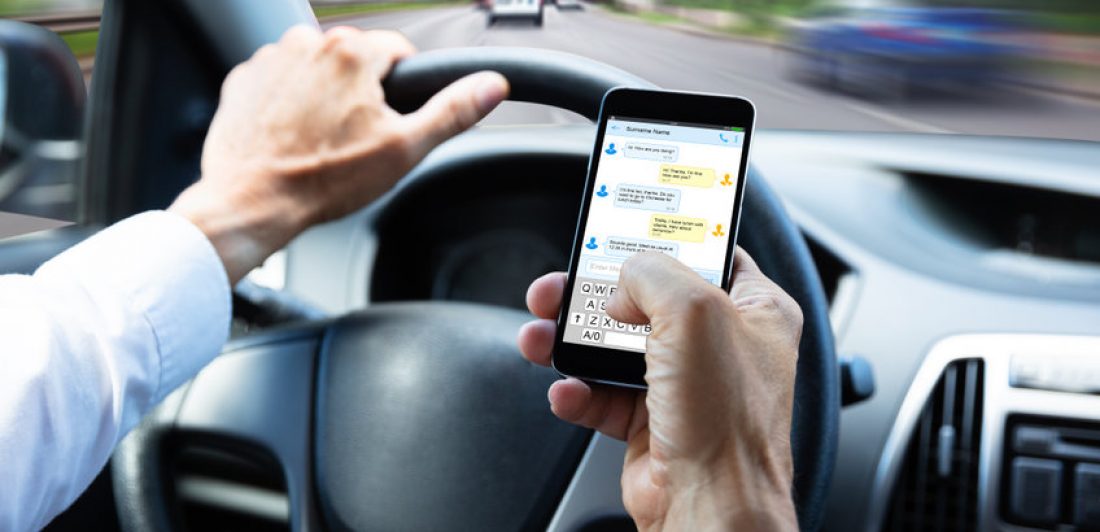 Man Typing Text Message On Mobile Phone While Driving Car Man texting on his cell phone while driving a cae