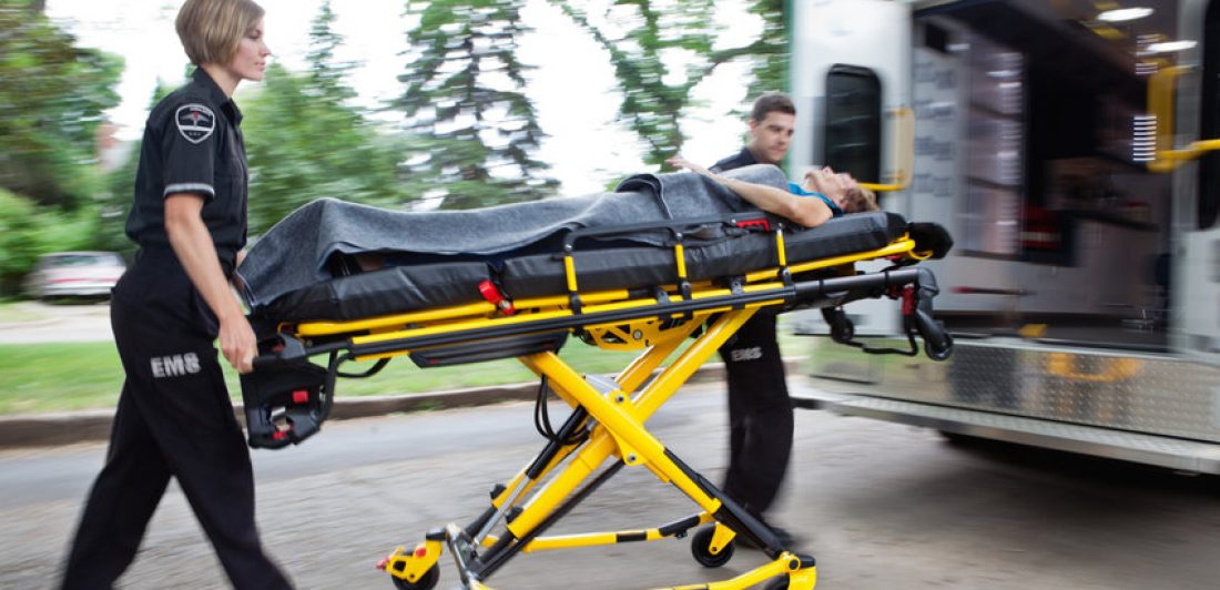 Image of paramedics loading an elderly woman into the ambulance on a stretcher