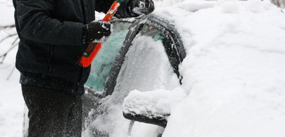 Machine, covered with snow. Image of a person scraping ice and snow from their car