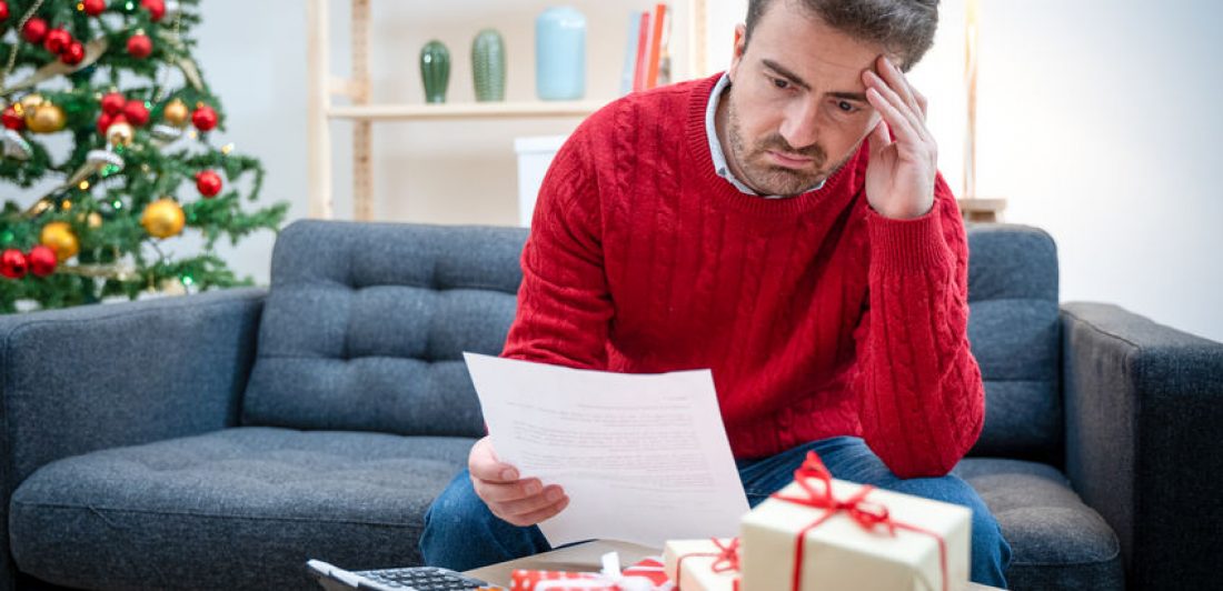 Man without money for christmas present Image of stressed out man with paperwork, a calculator, and a stack of gifts