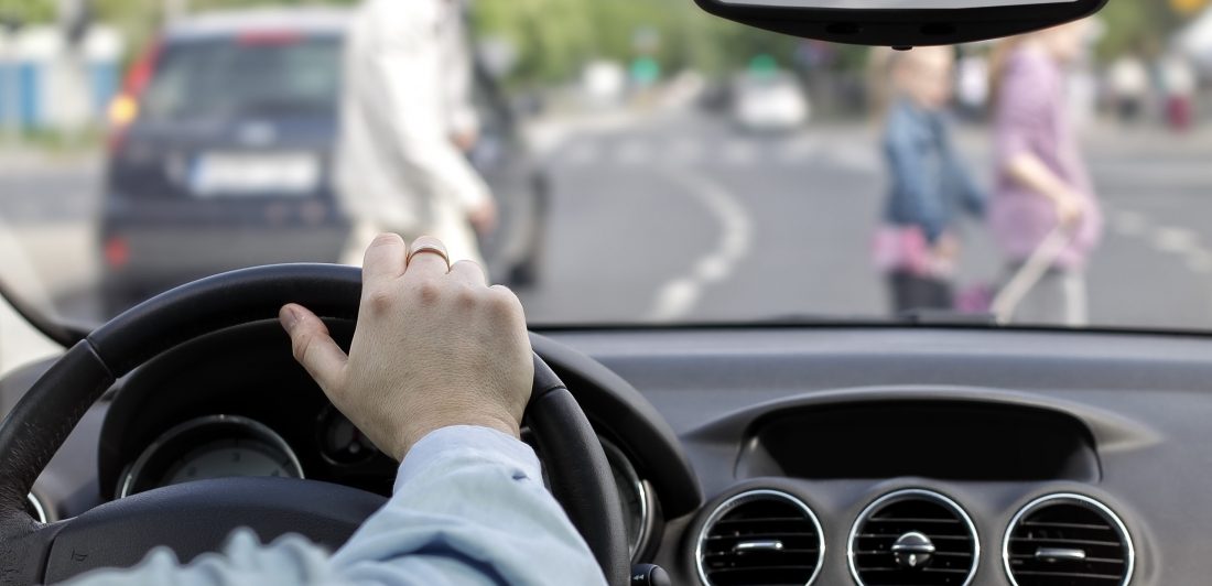 The driver and a pedestrian at a crosswalk Image of person driving a car with pedestrians in the crosswalk
