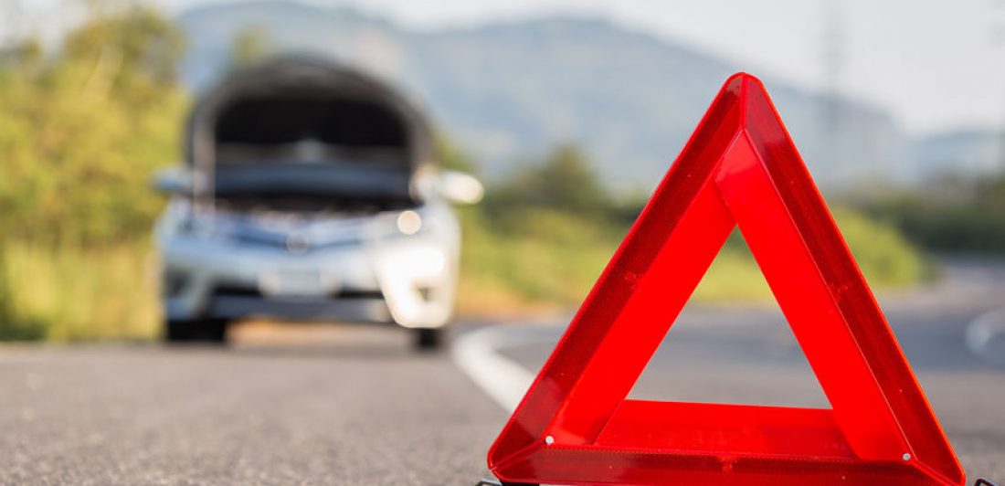Red emergency stop sign and broken car on the road Image of vehicle broken down on the side of the road with a red emergency triangle
