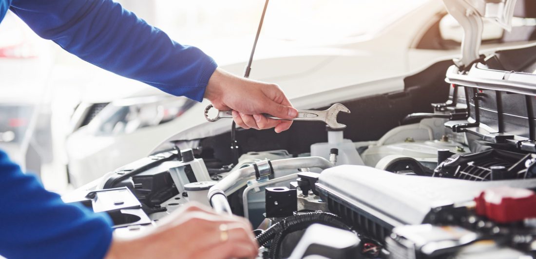 Hands of car mechanic with wrench in garage. Image of mechanic in garage with a wrench