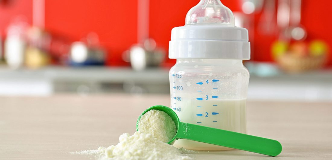 Feeding bottle and baby milk formula on kitchen background Image of a baby bottle on a counter with a scoop of baby formula