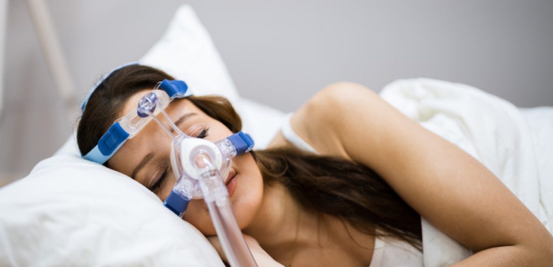 Sleep Apnea Oxygen Mask Equipment Image of woman wearing a CPAP mask while sleeping