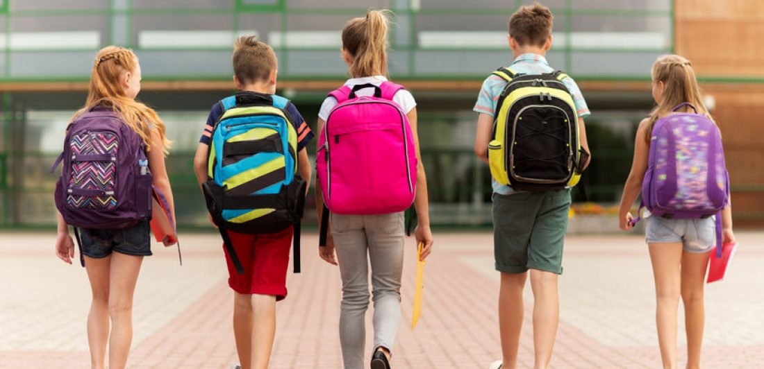 Image of 5 school children walking away from the camera with backpacks on