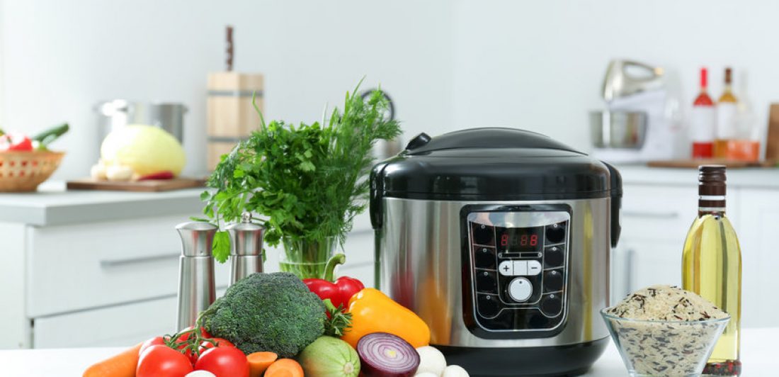 Modern multi cooker and products on kitchen table Image of pressure cooker on counter with rice and vegetables