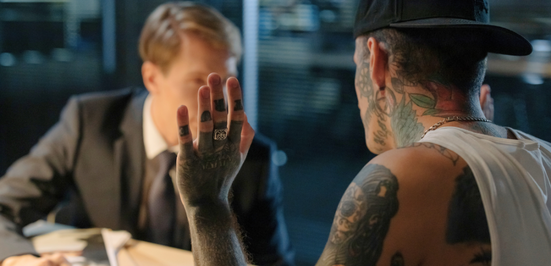 Self-incrimination Image of man with tattoos talking to man in suit