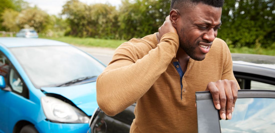 Male Motorist With Whiplash Injury In Car Crash Getting Out Of Vehicle Image of man holding his neck in pain after a car accident
