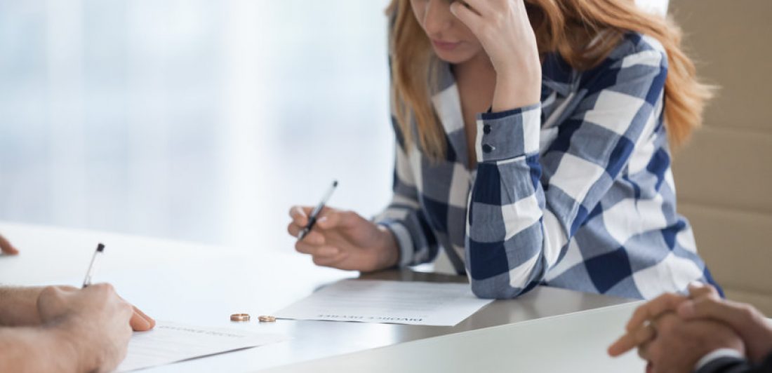 Serious wife signing divorce decree in lawyer office Image of woman signing a divorce decree