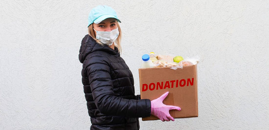 donations-1 Image of a woman in a mask with gloves carrying a donations box