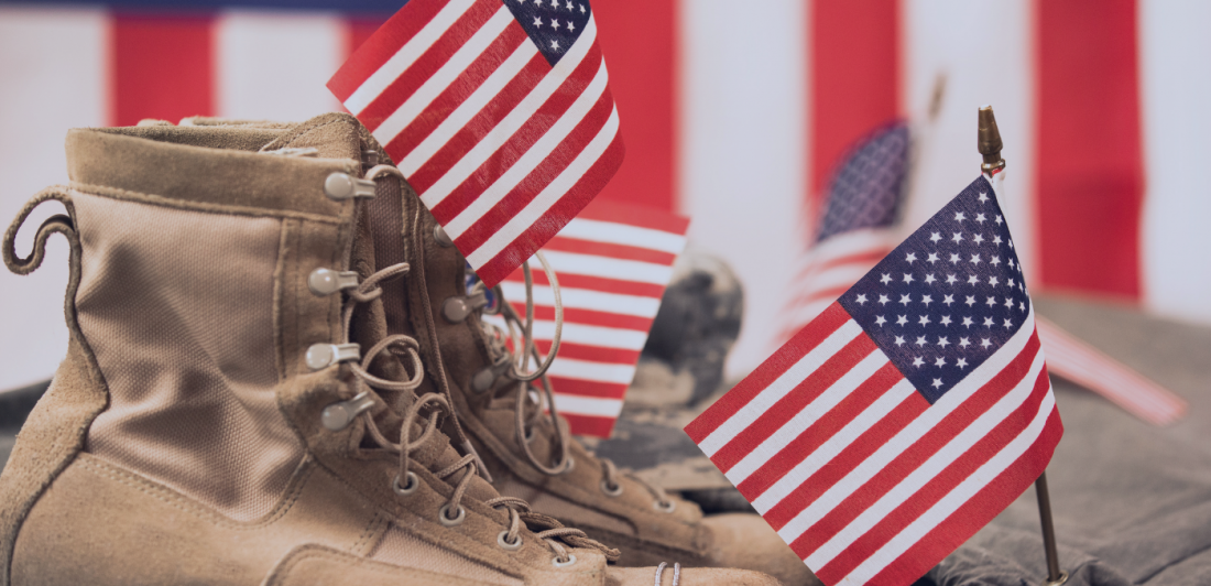 Military combat boots with dog tags and American flags displayed in remembrance of fallen service members