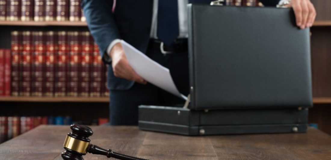 Image of attorney behind a gavel putting paperwork in a briefcase
