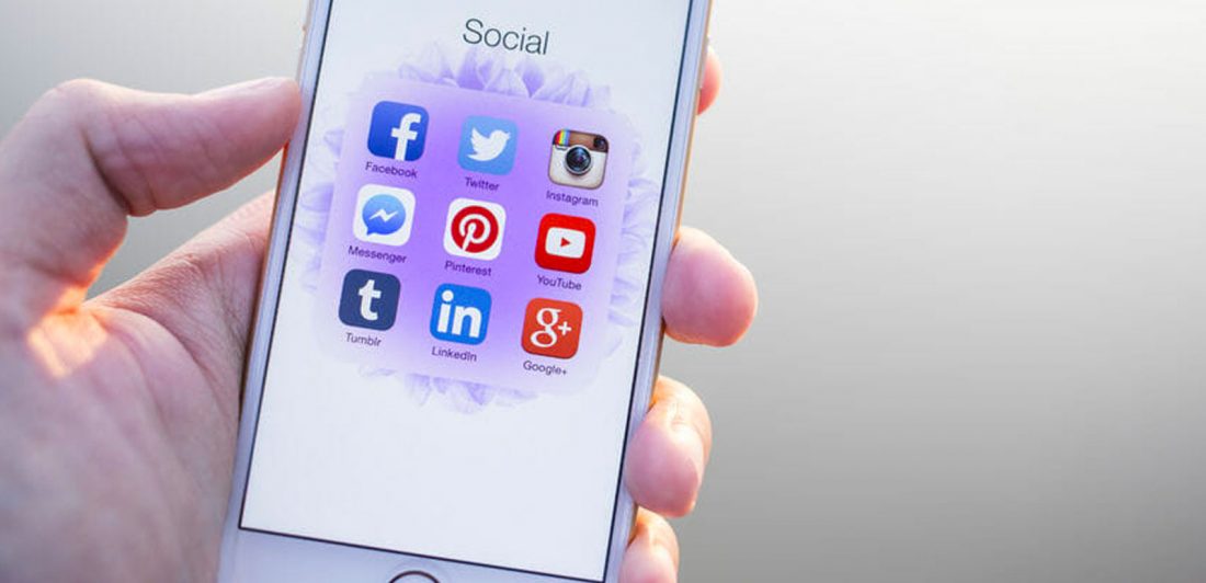 post-careless-social-media-can-hurt-lawsuit Image of person holding their cell phone with social media icons displayed on the screen