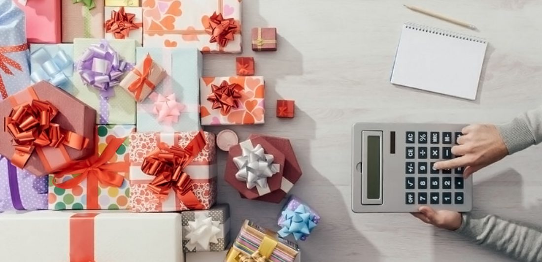 post-holiday-budgeting Image of various brightly wrapped gifts and a person making calculations on a calculator with a pen and pad