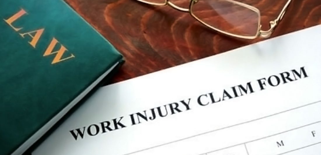 post-injured-at-work-lawsuit Image of work injury claim form, glasses, and law book