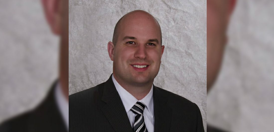 Image of a man in a black suite with a black and white tie and white button up shirt