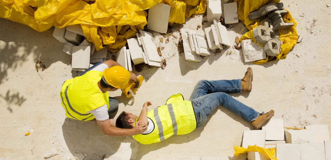post-workplace-slip-and-fall Image of injured construction worker in safety gear on a worksite being assisted by coworker