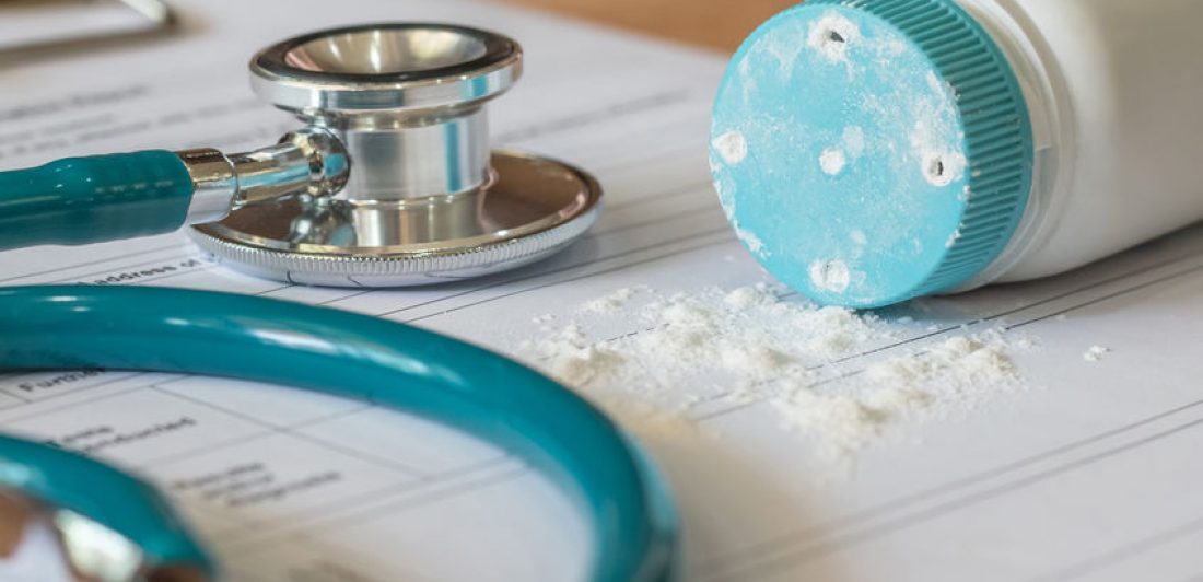 Baby powder product with talc mineral spilling over diagnosis re Image of stethoscope, paperwork, and talc powder spilling on table